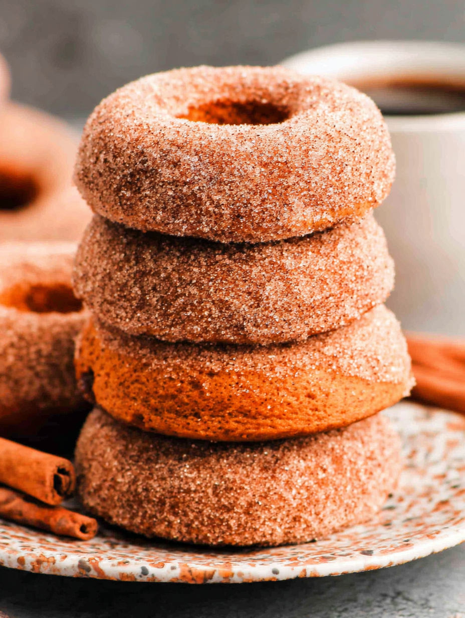 Pumpkin spice baked donuts stacked on a plate.