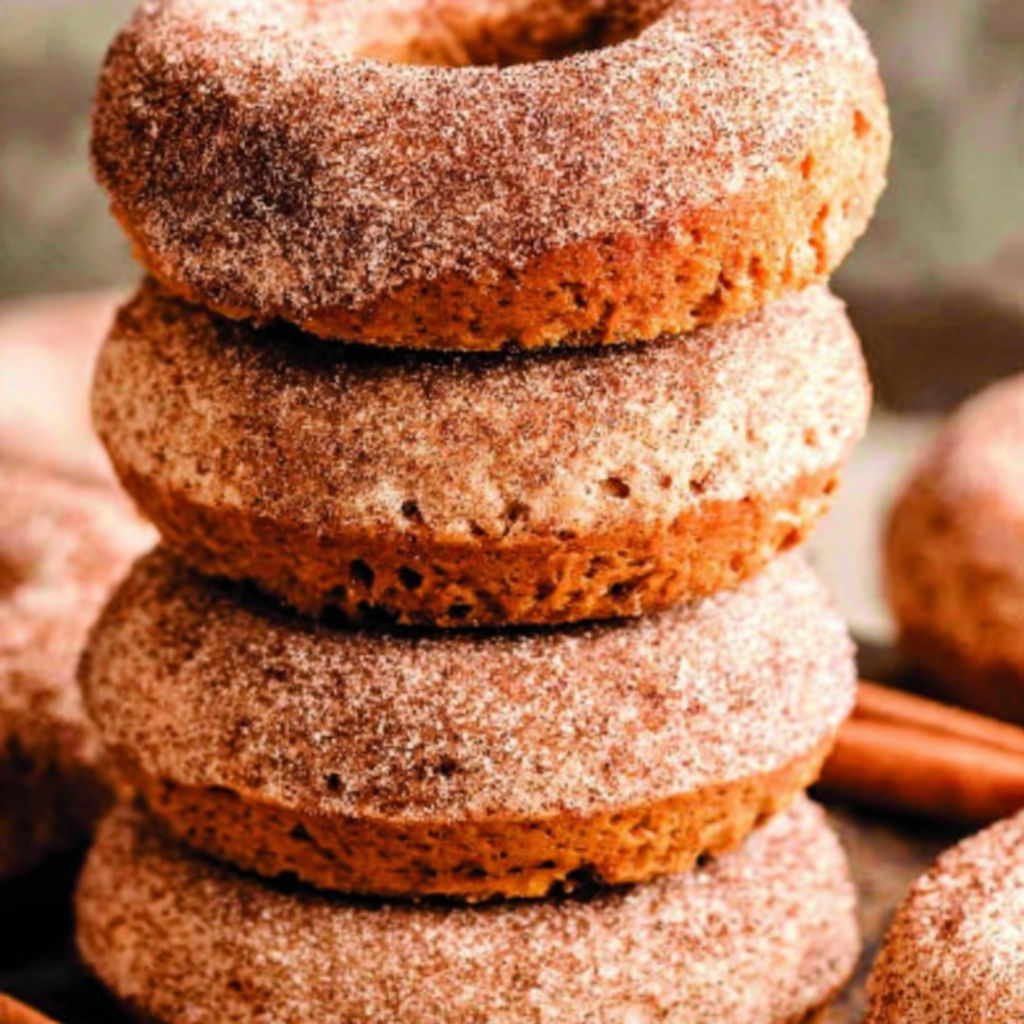 Pumpkin spice baked donuts stacked on a table.