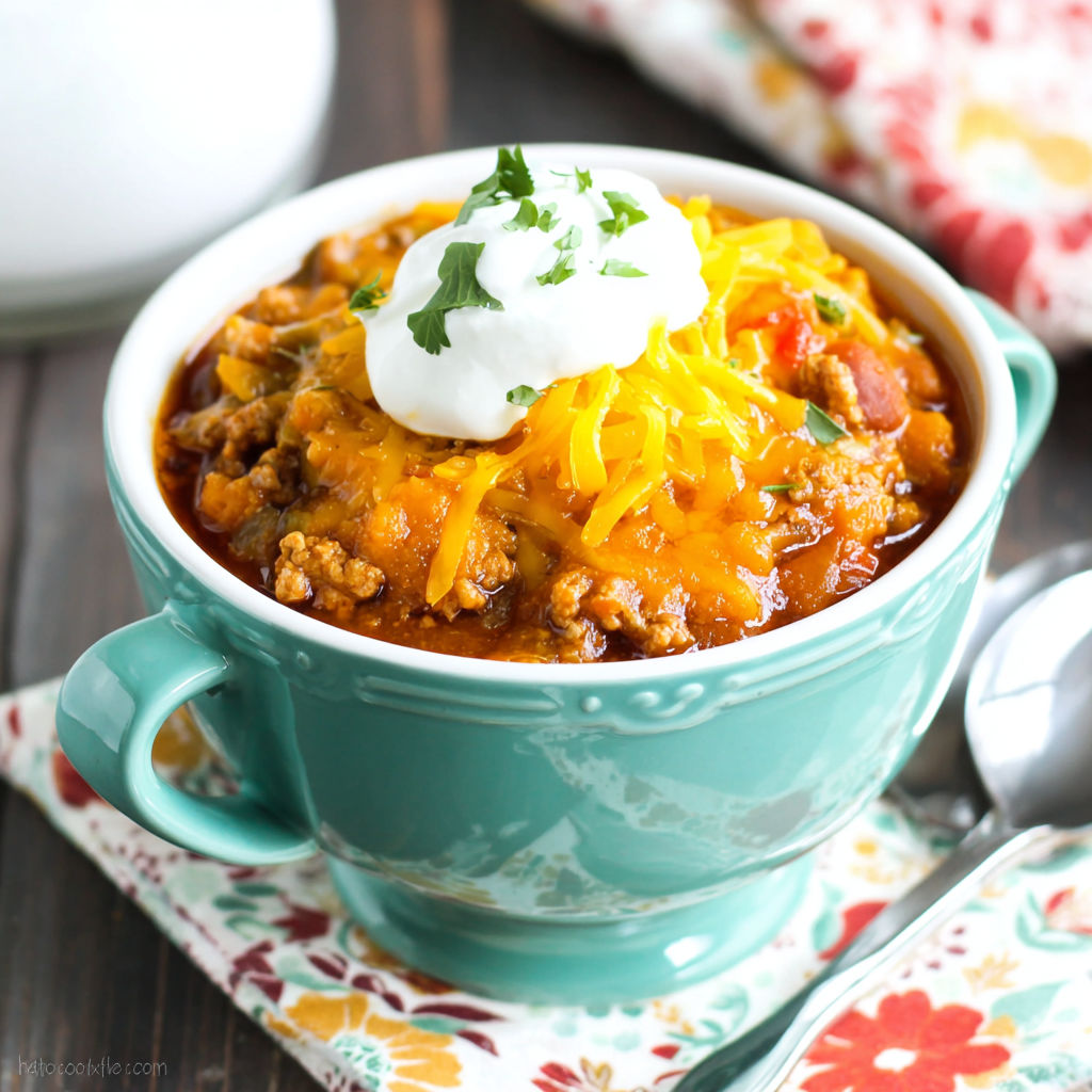 A bowl of chili with a dollop of sour cream on top.