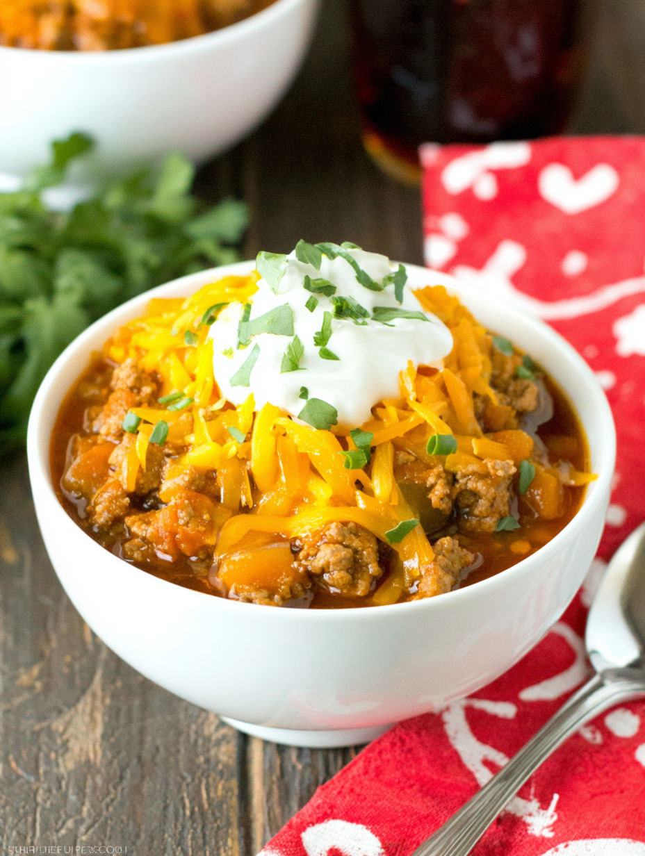A bowl of chili with cheese and sour cream on top.