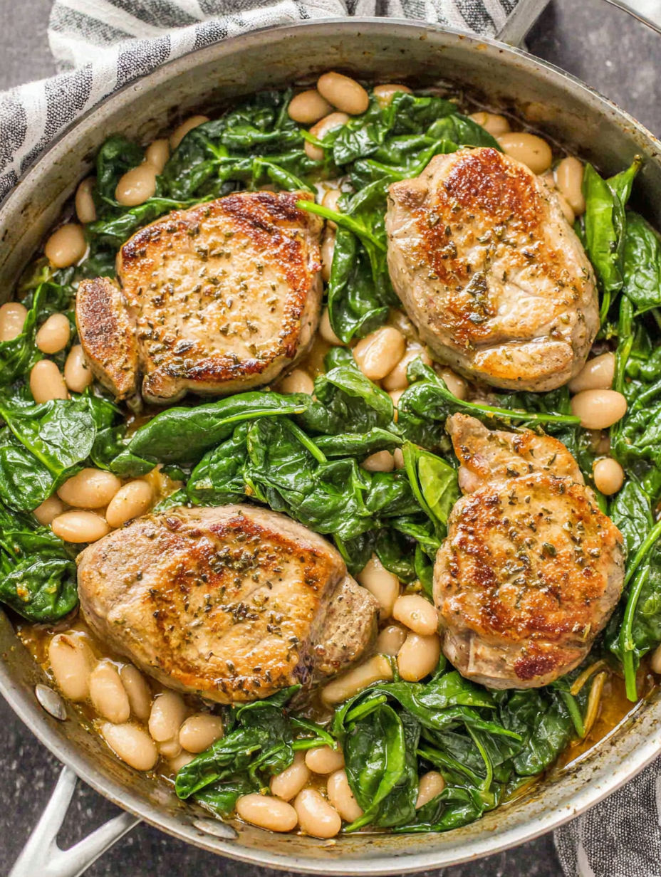 A skillet dinner with pork chops, white beans, and spinach.