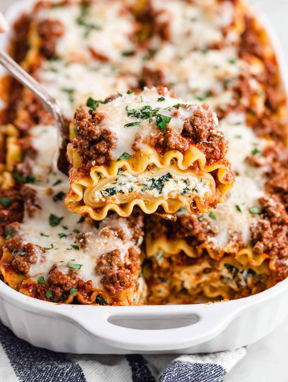A dish of lasagna roll-ups with cheese and meat.
