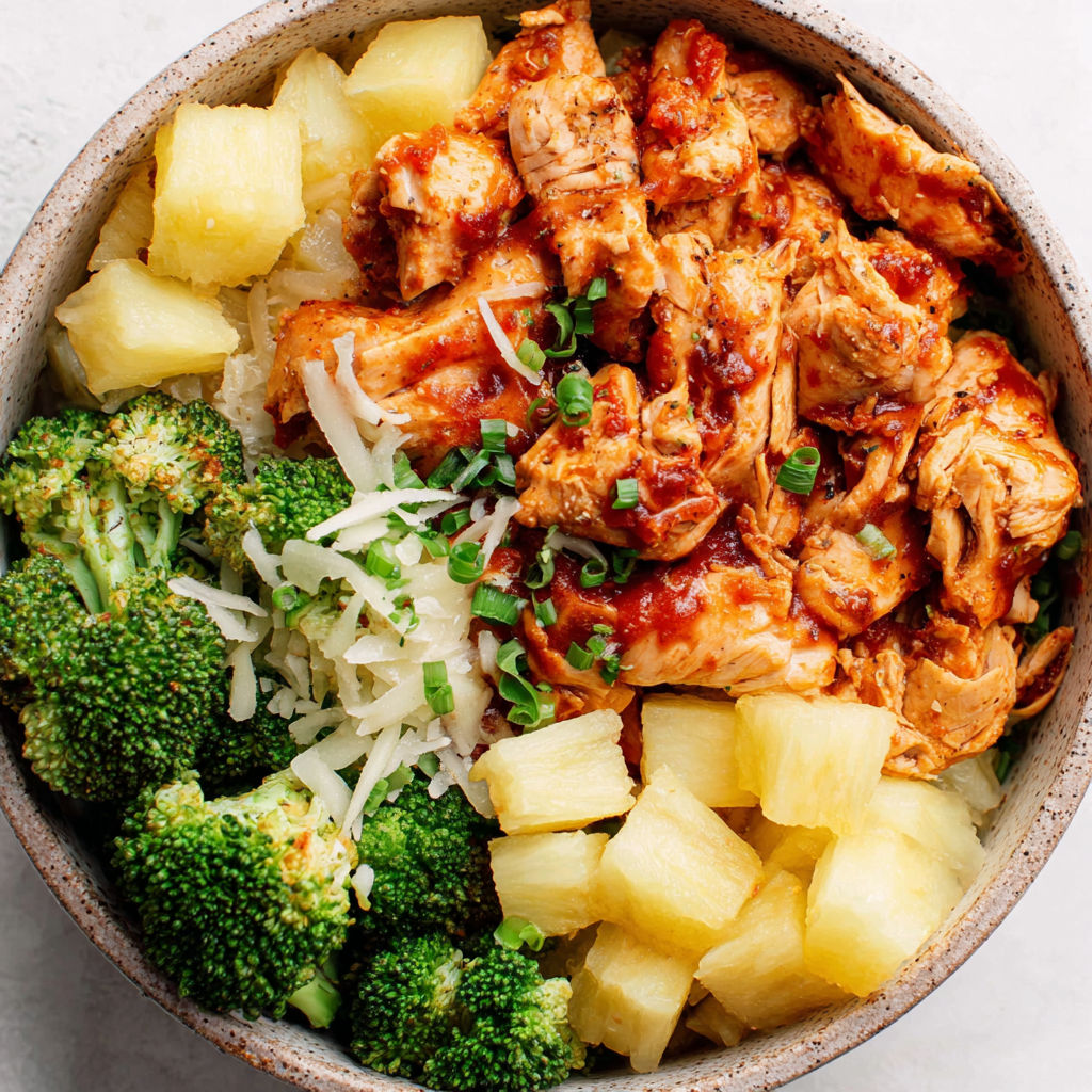 A bowl of food with chicken and pineapple.