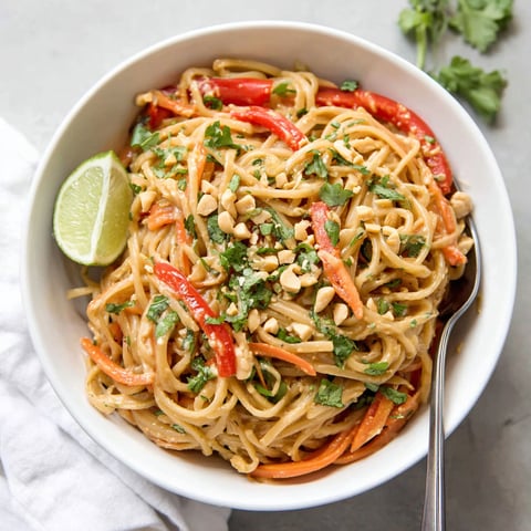 A bowl of noodles with peanut butter and vegetables.