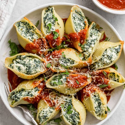 A plate of stuffed shells with sauce.
