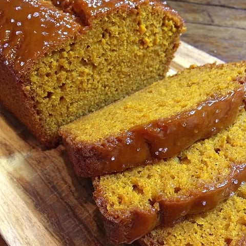 A slice of pumpkin bread on a wooden cutting board.