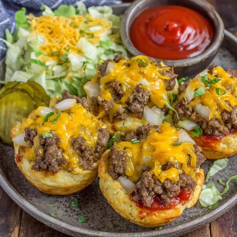 Two cheeseburger cups with lettuce and tomato on top.