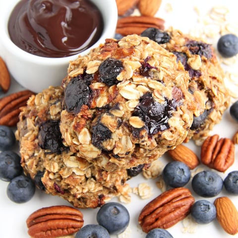 A bowl of oatmeal with chocolate sauce and blueberries.