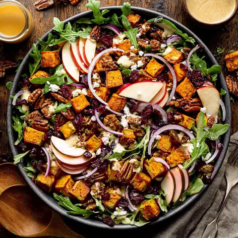 A bowl of salad with roasted sweet potato.