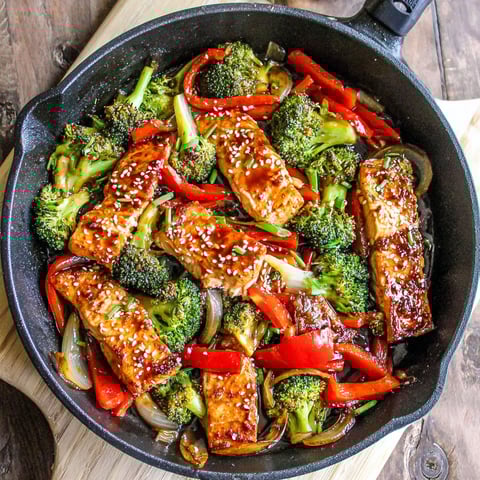 A pan of baked chicken with broccoli and peppers.