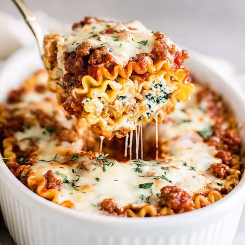 A fork is being used to pick up a piece of lasagna.