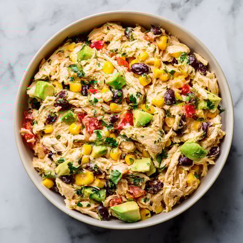 A bowl of chicken salad with avocado, tomatoes, corn, and black beans.